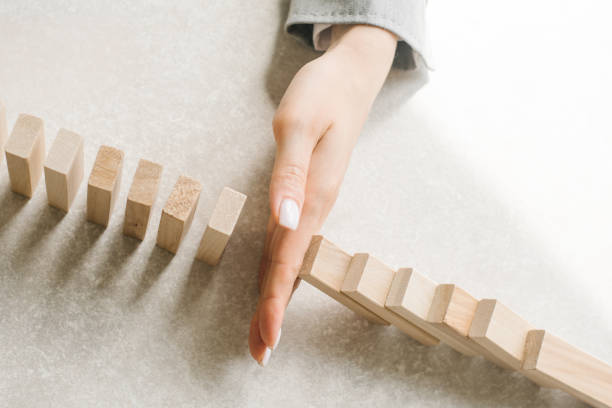 a hand preventing dominoes from falling