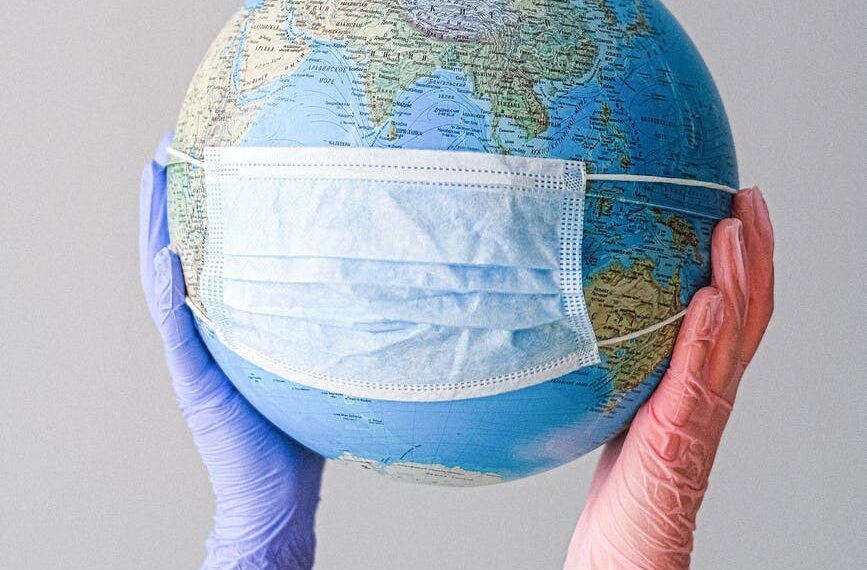 hands with latex gloves holding a globe with a face mask