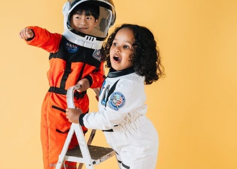 positive diverse children in astronaut costumes in studio